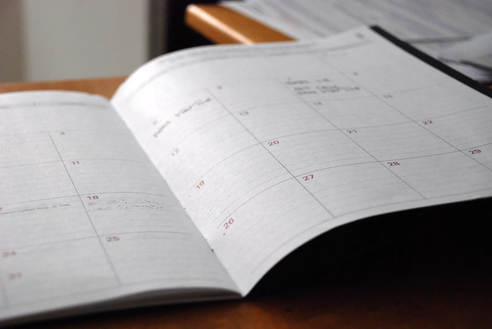 Open monthly planner with handwritten notes lying on a wooden desk