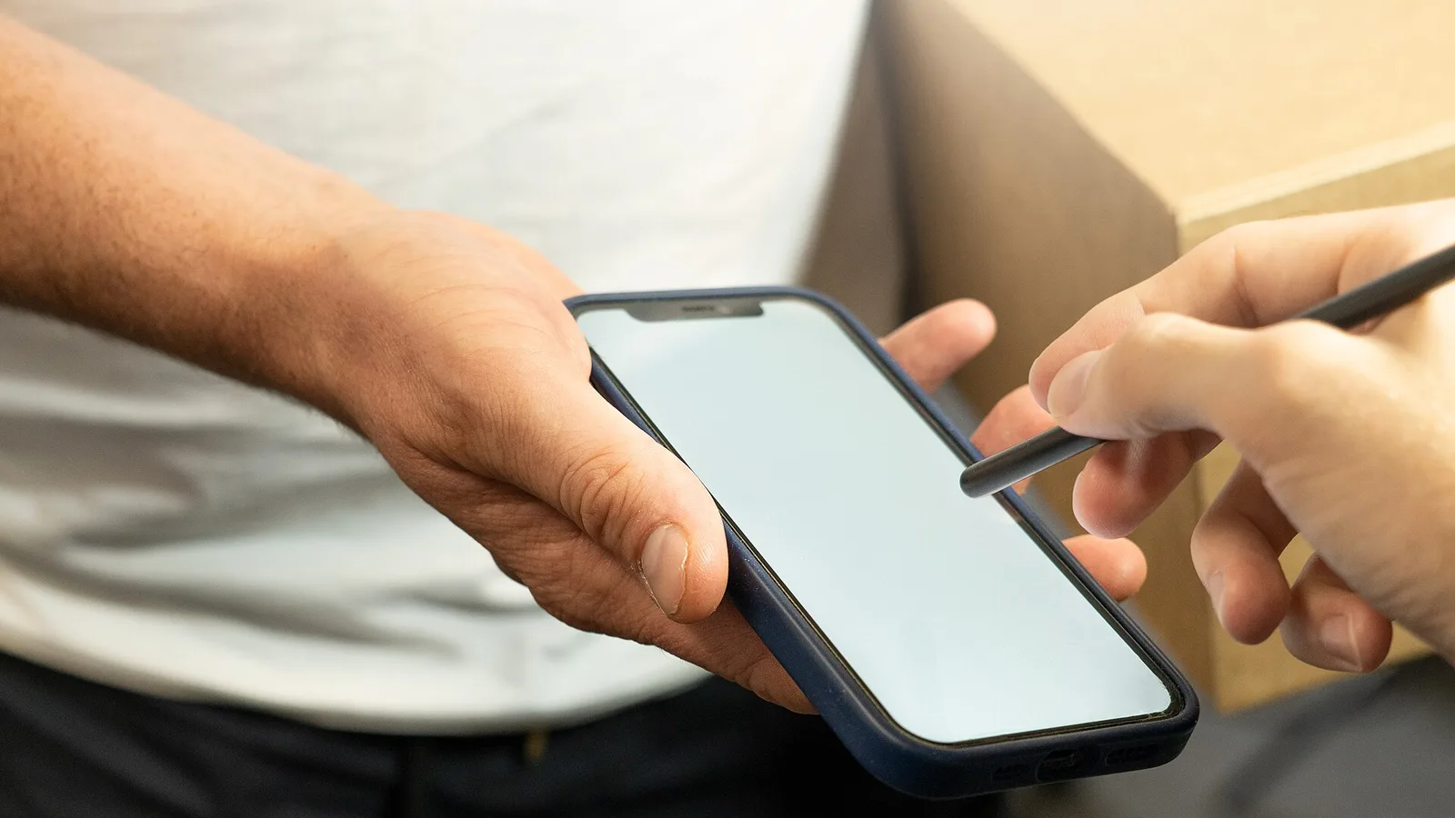 Person signing on a smartphone screen with a stylus