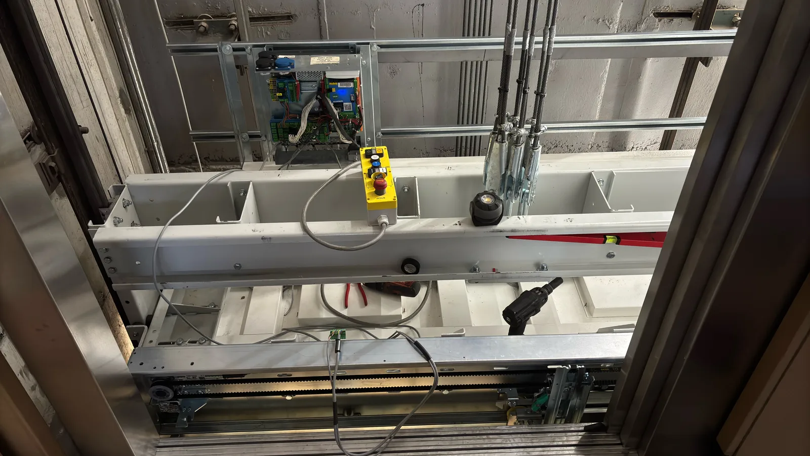 Open lift car roof during elevator maintenance with control box and tools
