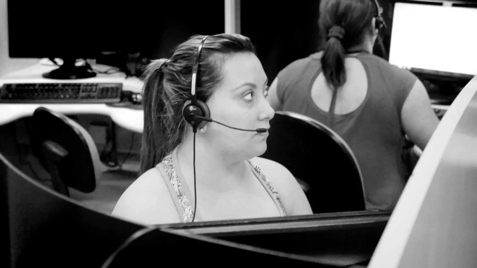 Customer support agent wearing a headset at a helpdesk workstation