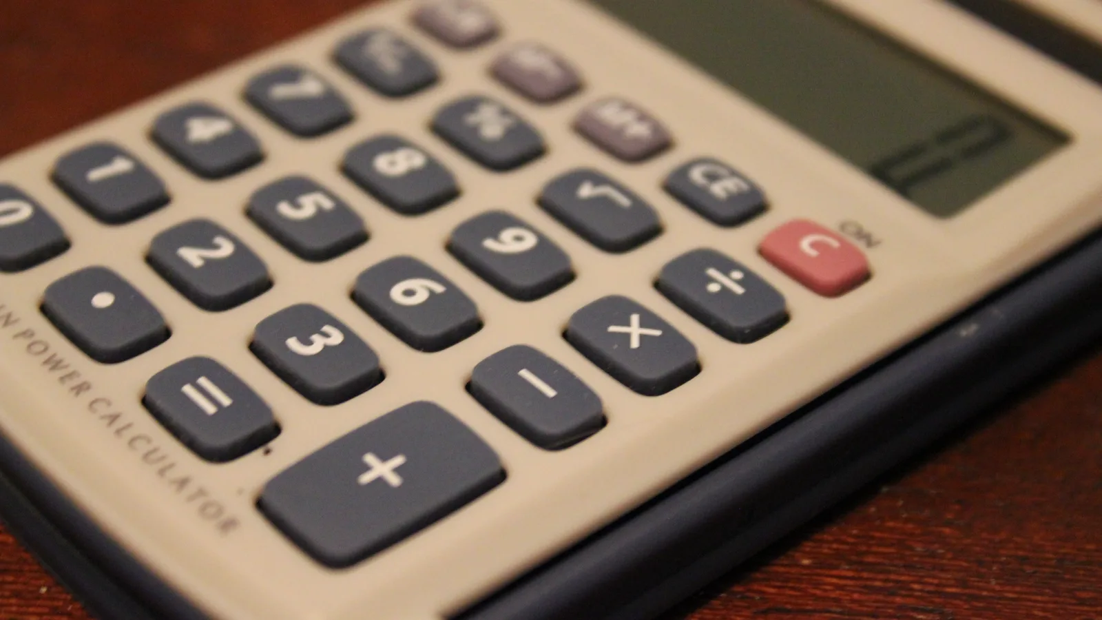 Close-up of the keypad of a desktop calculator resting on a wooden desk