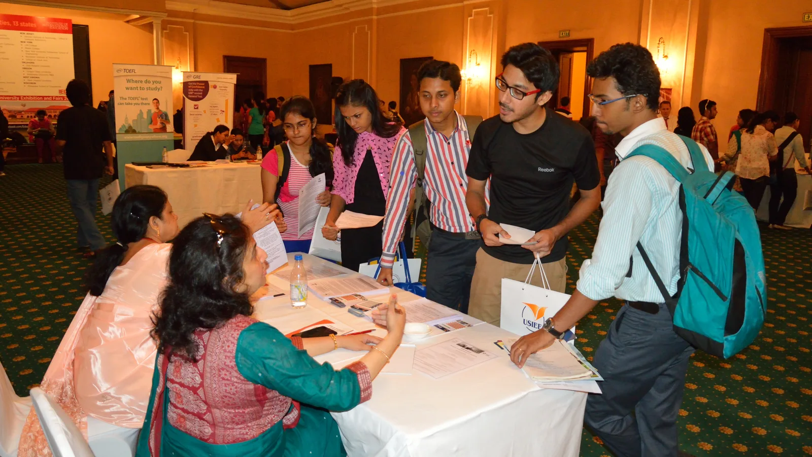 Students enquiring with admissions counsellors at a desk during an education fair in Kolkata