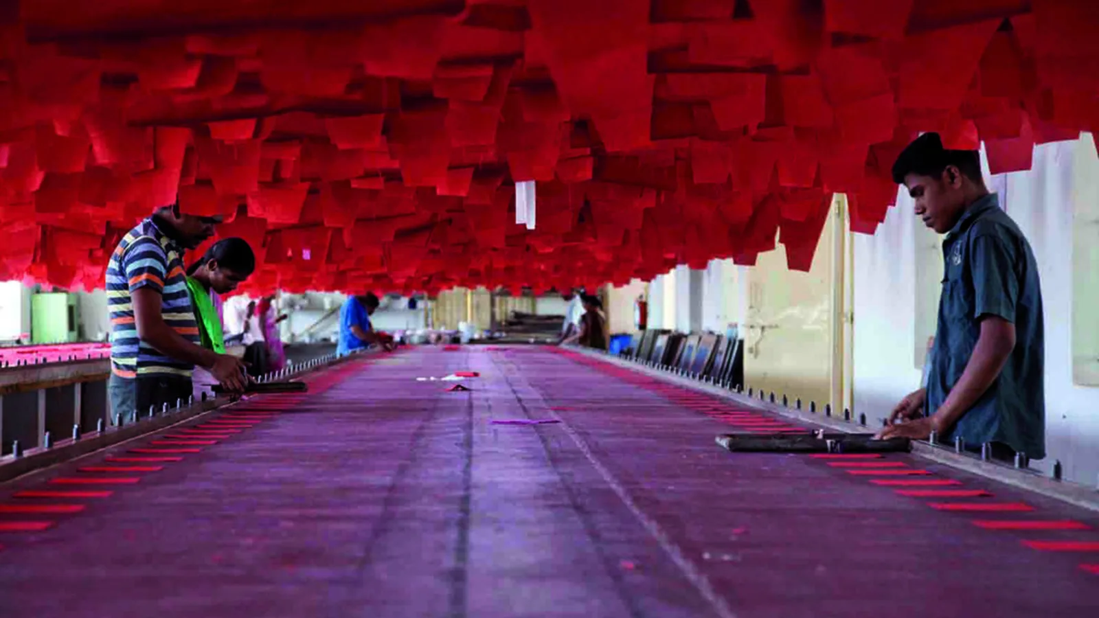 Workers at long printing tables on a textile factory floor in India