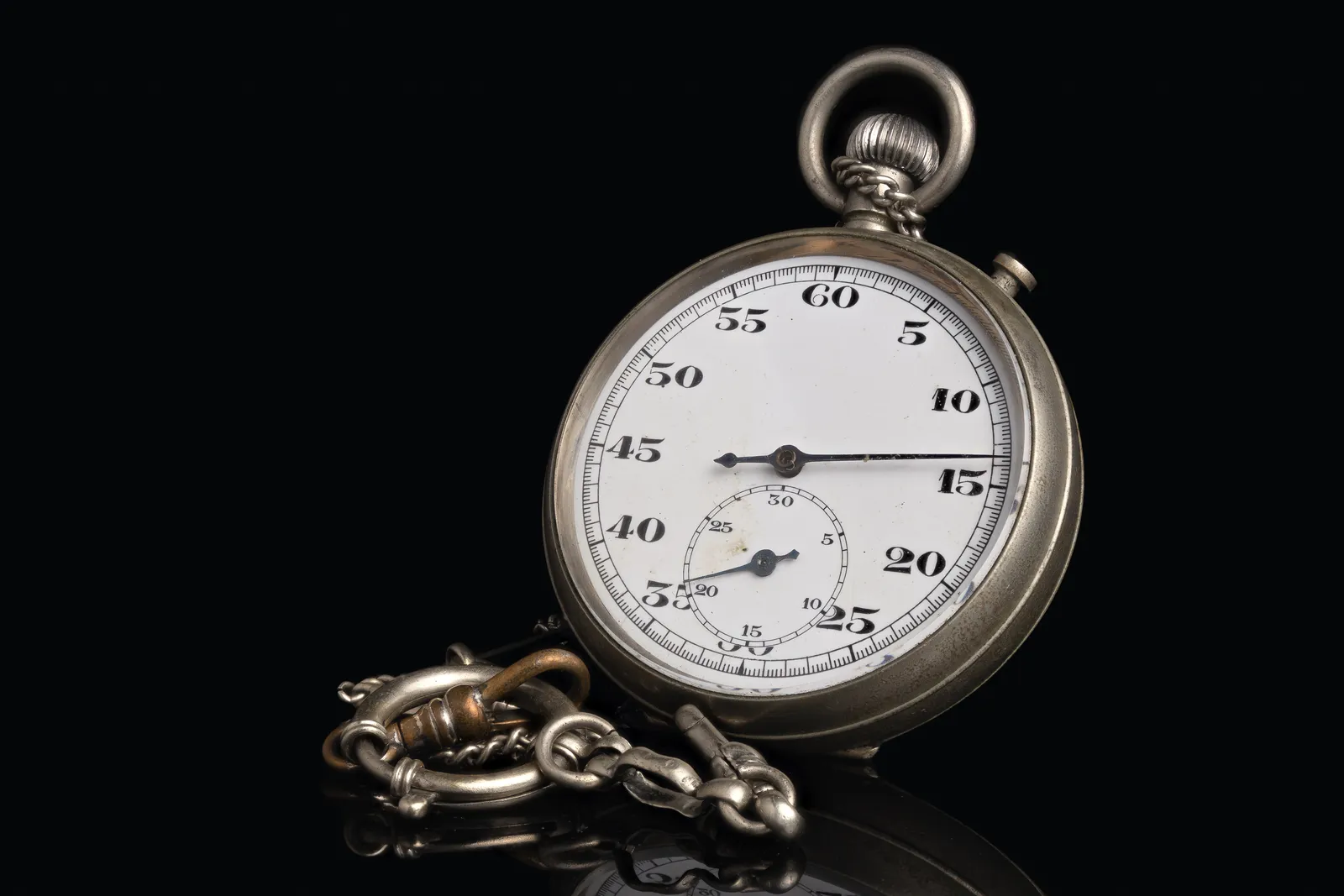 Vintage silver stopwatch with a white dial and chain on a black background