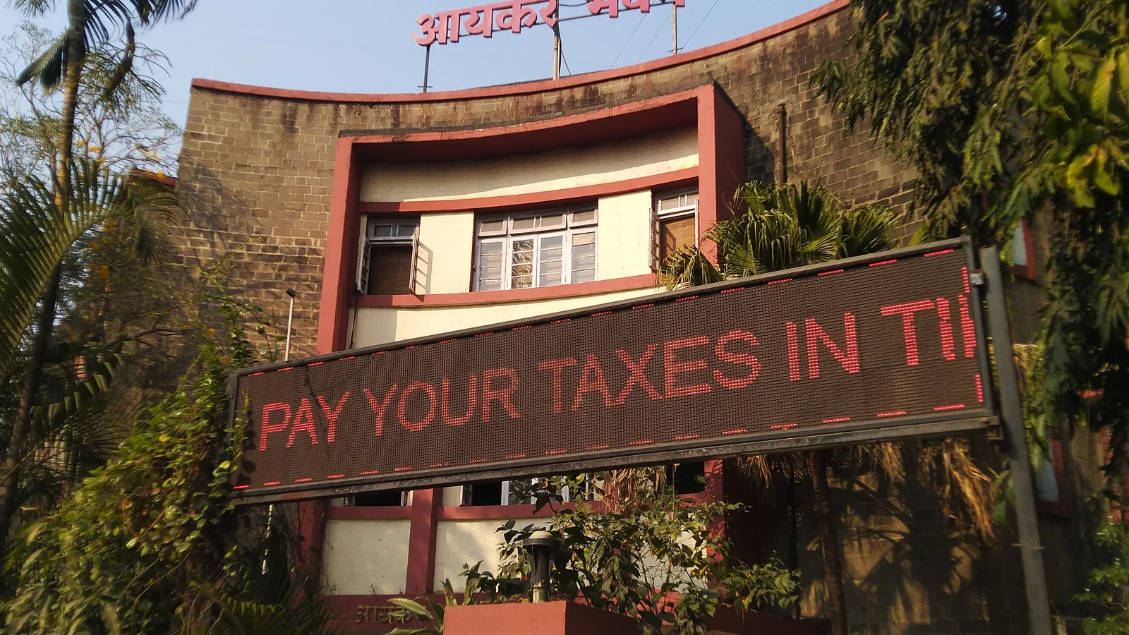 Aaykar Bhavan income tax office building in Pune with an LED sign reading Pay your taxes in time
