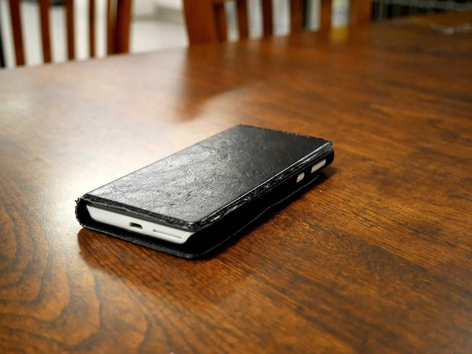 Smartphone in a black flip case lying on a wooden table
