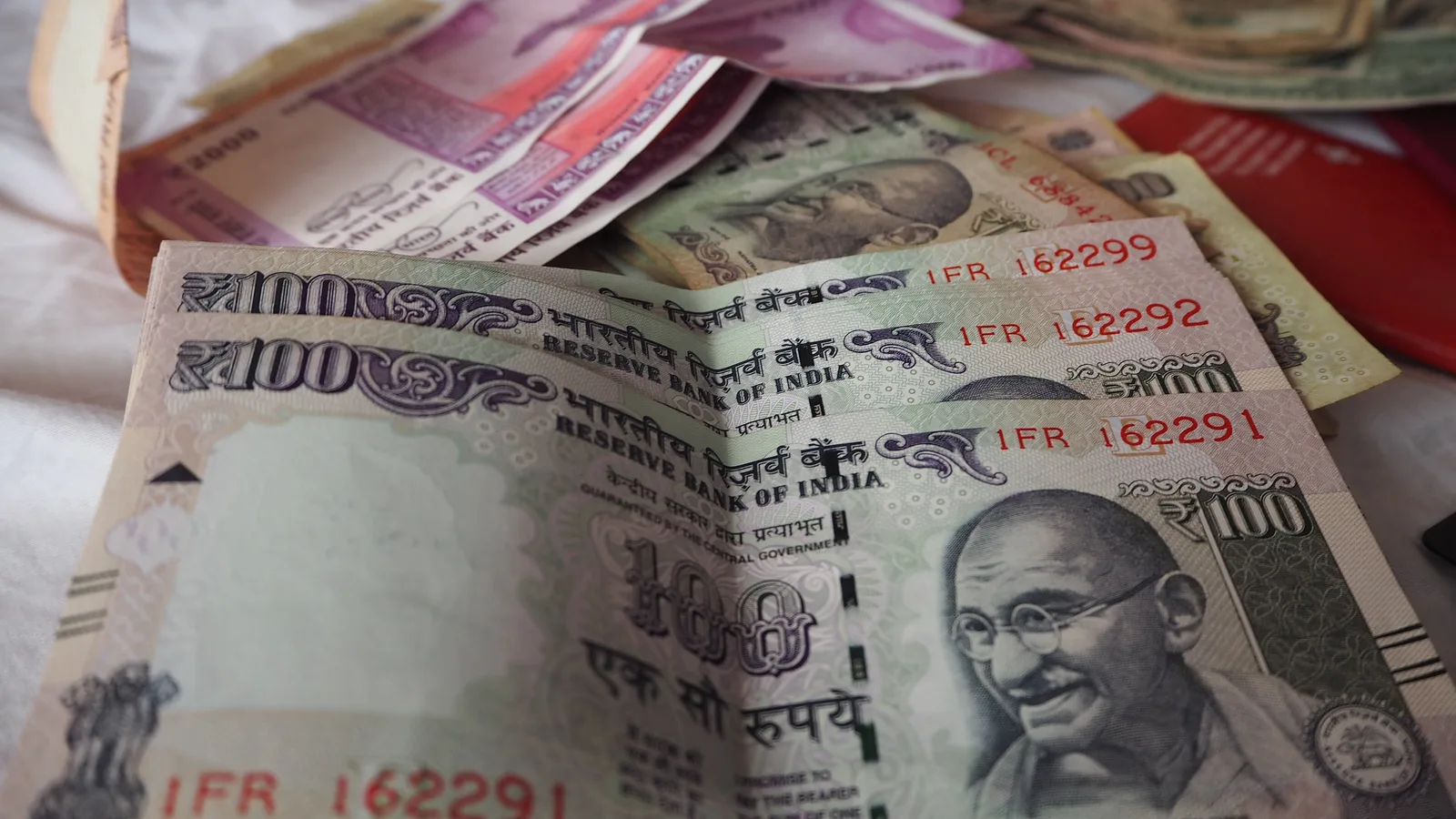 Indian 100 and 2000 rupee banknotes spread out, representing salary payouts